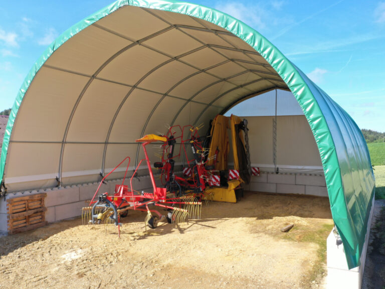 AGROTEL Rundbogenhalle befestigt auf zwei Reihen Betonblocksteinen. Für zusätzliche Einfahrtshöhe.