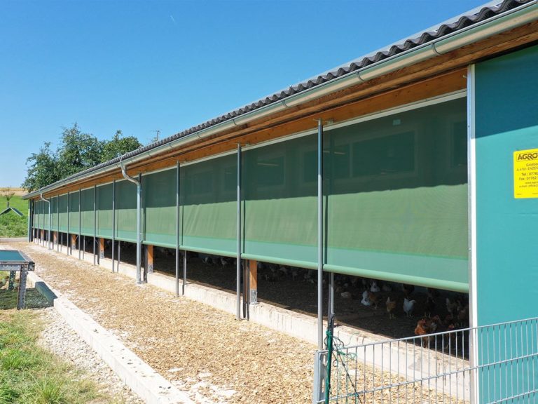 Aufrollbares Windschutzsystem an Hühnerstall als Öffnung zum Freilauf