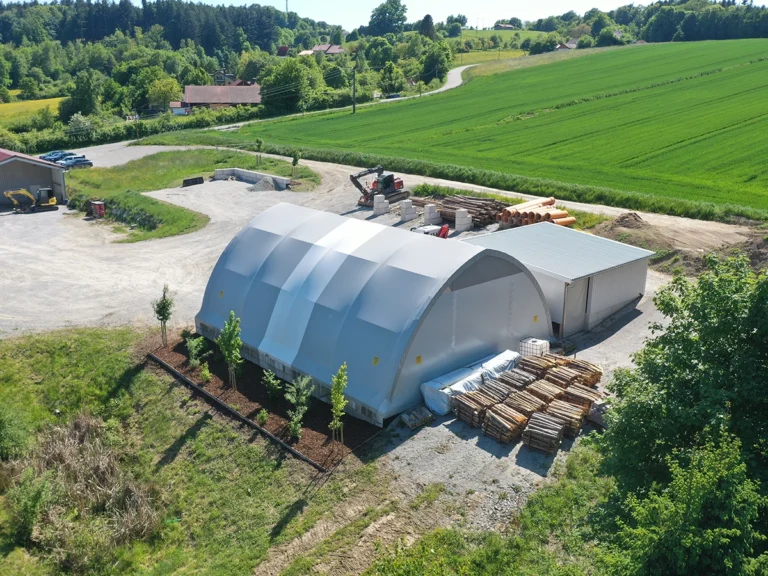 Profilträger-Rundbogenhalle mit mittigem Lichtband für extra viel Tageslicht im Inneren und Netzgiebel zur Luftzirkulation