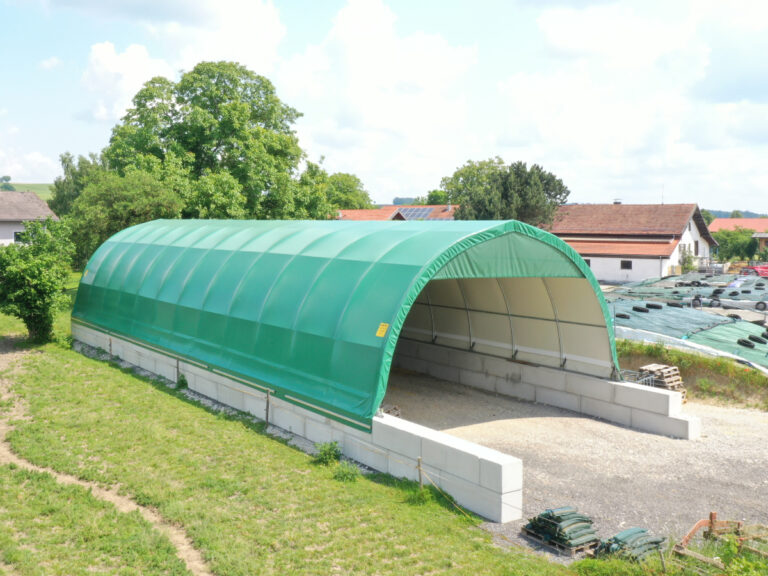 Rundbogenhalle auf Betonblocksteinen genutzt als Lagerhalle für Maschinen, Heu und Stroh