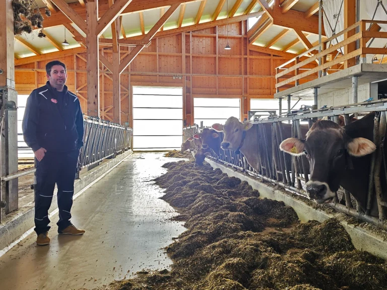 Markus Bichler in seinem neuen Milchviehstall mit natürlicher Belüftung durch großflächige Windschutzsysteme und Rolltore
