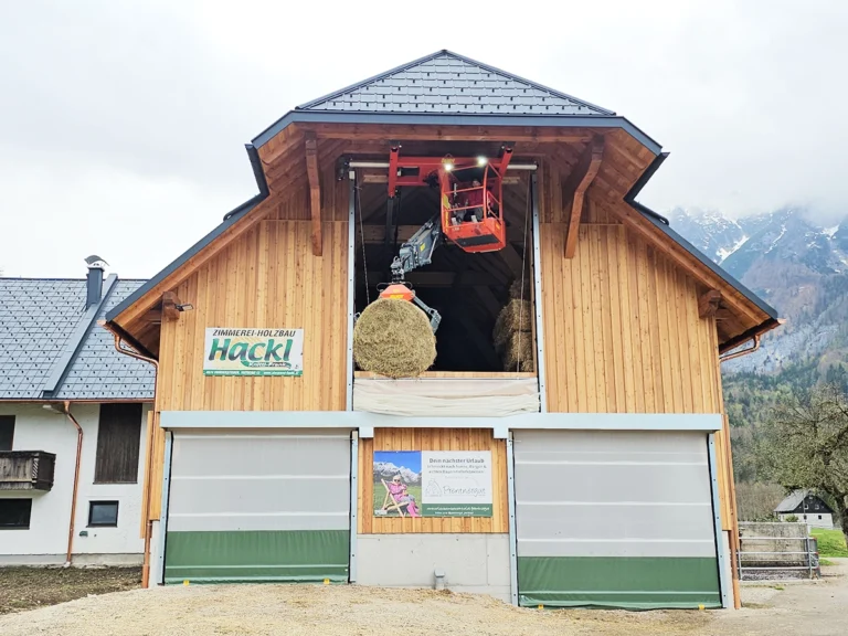 Heukran fährt durch speziell entwickeltes Hallentor zur Aufnahme und Lagerung von Heuballen