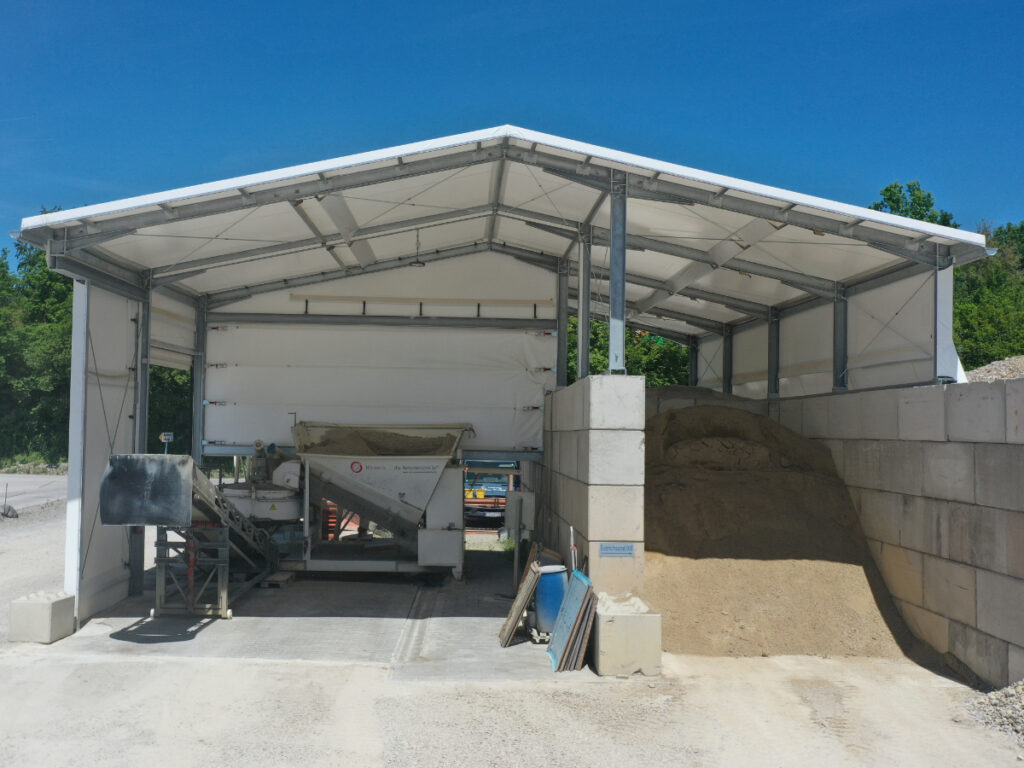 Maßgefertigte Schüttgut-Überdachung und Maschinenhalle für den Baggerbetrieb Ortlieb in der Kiesgrube