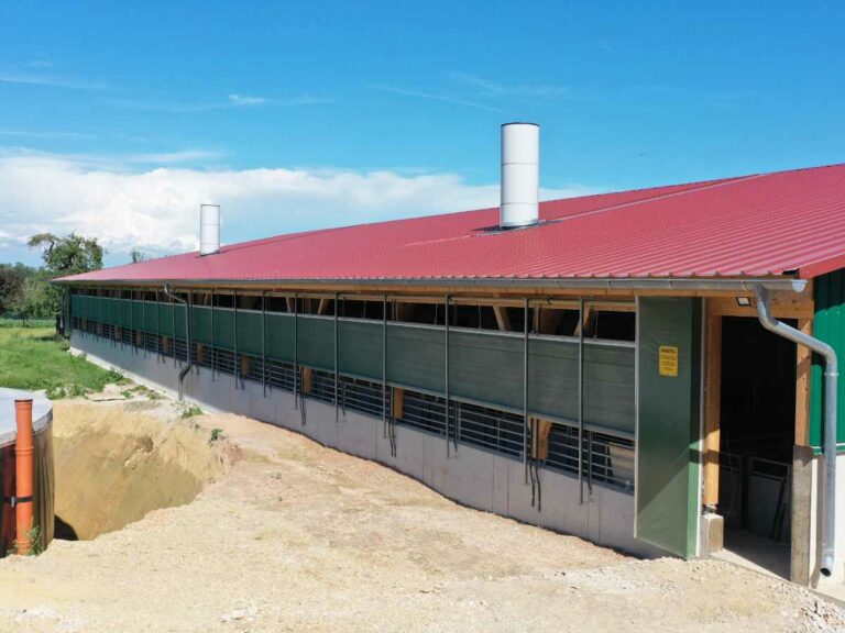 Außenansicht des Schweinestalls Friedl mit großflächigen Windschutz-Curtains von AGROTEL