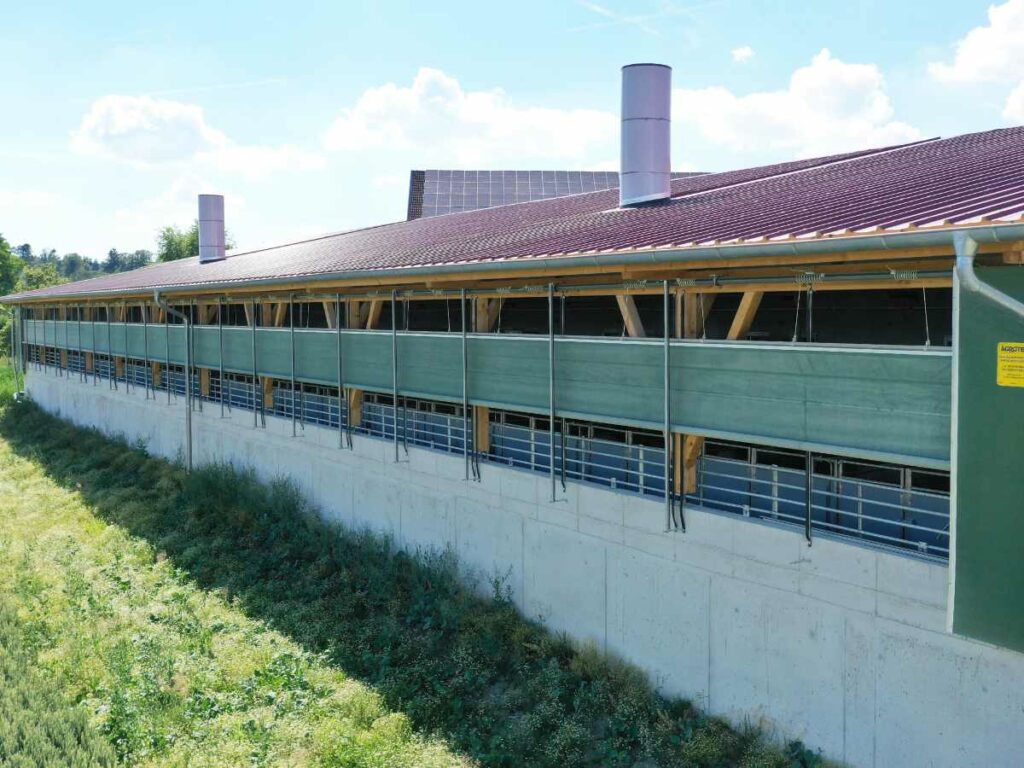 Windschutzsystem WSS4 an der Längsseite eines Schweinemaststallt mit überdachtem Auslaufbereich.